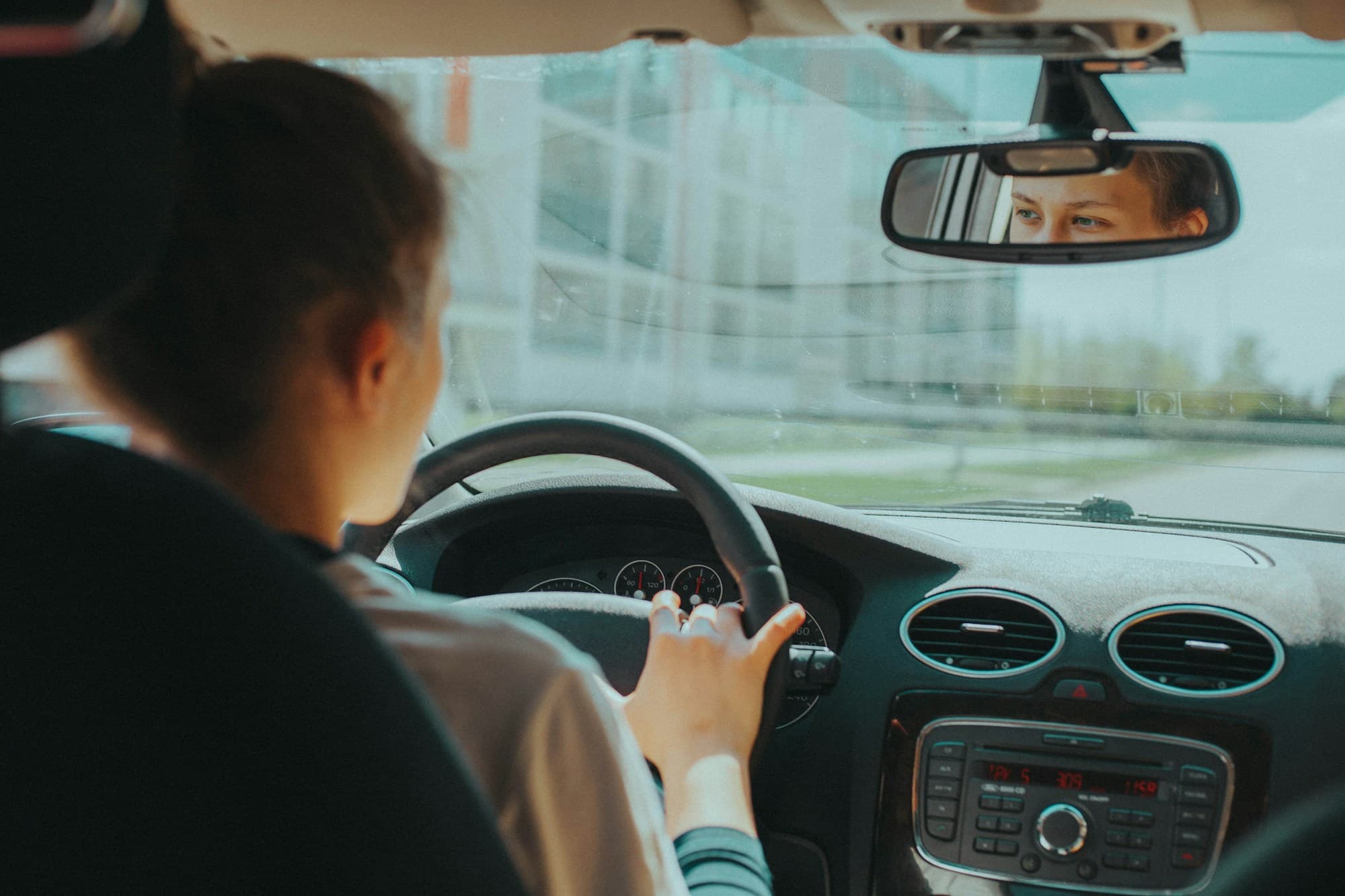 A driver's eyes reflected in the rear-view mirror while checking behind before pulling away